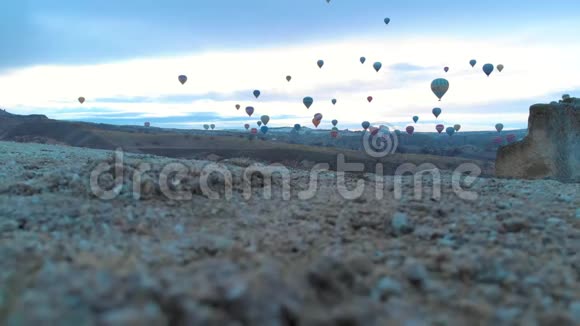 土耳其卡帕多西亚日出时天空晴朗天空中有许多热气球的空中山谷景观视频的预览图
