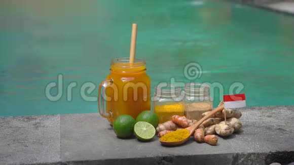 一个男人的手从游泳池旁边拿着一杯全国巴厘岛饮料Jamu视频的预览图