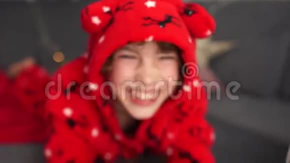 一个穿着红色睡衣戴着头巾的鹿的英俊蓝眼睛男孩的亲密肖像平安夜圣诞节视频的预览图