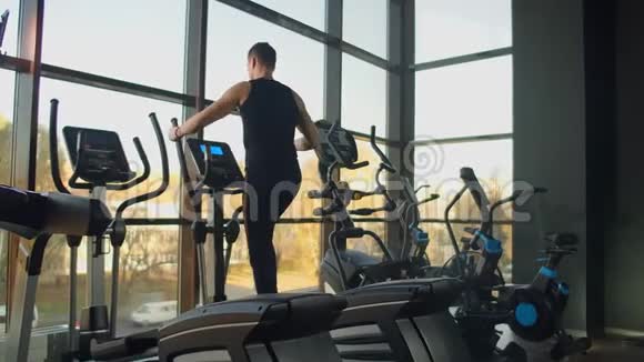 肖像健身男子在健身俱乐部椭圆交叉教练训练前热身近距离男性训练视频的预览图