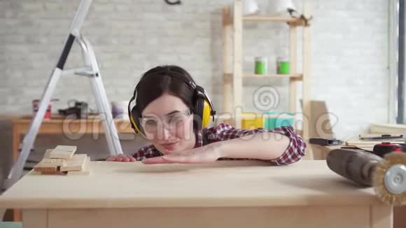 特写年轻的职业木匠女人从桌子上吹木刨花慢悠悠地视频的预览图