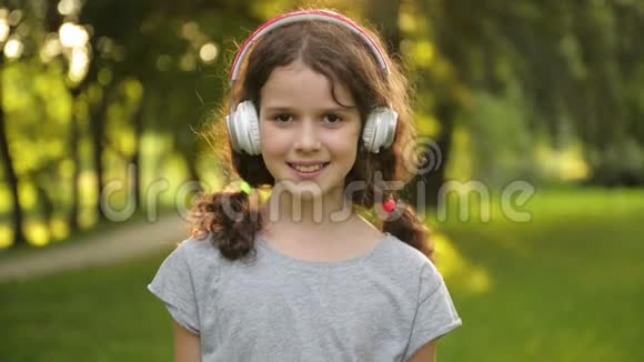 漂亮的棕色眼睛带耳机的白人小女孩的肖像快乐的微笑儿童视频的预览图