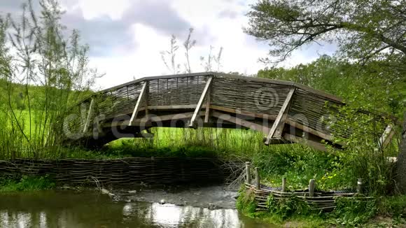 用编织柳条栏杆横跨小溪的木桥视频的预览图