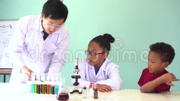 年轻的科学家拿着烧瓶教两个非裔美国人混合孩子做化学实验视频的预览图