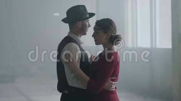 肖像男子戴着费多拉的帽子古典西装和女人穿着风格的布在废弃的建筑里跳舞视频的预览图