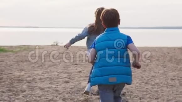 两个孩子沿着沙滩向海滨跑去视频的预览图