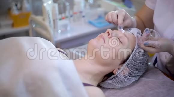 美容诊所年轻女子得到专业的面部治疗美容师在女性脸上做按摩脸面视频的预览图