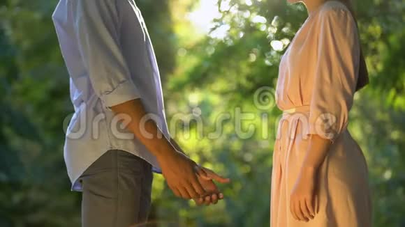 年轻的美国黑人男孩温柔地牵着女朋友的手第一次在公园约会视频的预览图