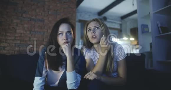 一个女孩在家里看恐怖电影时吓着她的朋友青少年友谊千禧年电影生活方式视频的预览图