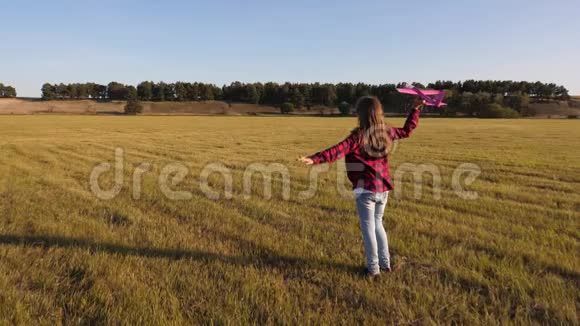 一个留着长发的十几岁的女孩在一个带着飞机的田野里玩耍他朝前飞去孩子梦想成为一个视频的预览图