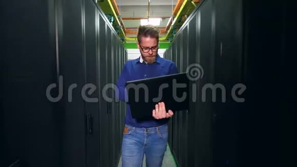 带笔记本电脑的男技术员正在服务器机房里视频的预览图