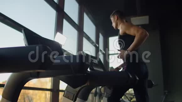 年轻的运动男女在运动健身房的跑步机上锻炼和跑步在大的全景窗户附近视频的预览图