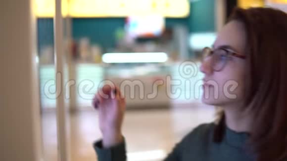 一位年轻女子在购物中心的触摸终端点菜现代技术在食品法庭上视频的预览图