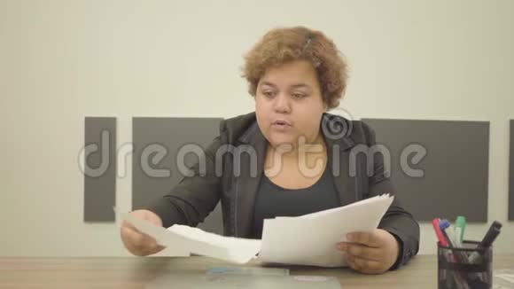 肖像丰满的女人穿着正式服装坐在办公室的桌子上做文书工作特写经理很忙视频的预览图