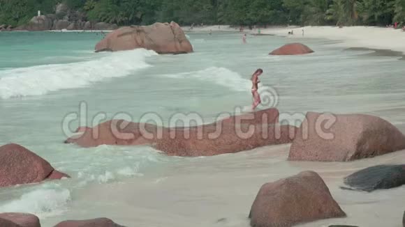 塞舌尔普拉斯林岛干净的海浪在沙滩上翻滚大石头躺在沙滩上的背景视频的预览图