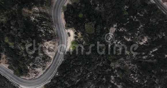 一辆黑色汽车在树林中的一条弯曲的公路附近的空中拍摄视频的预览图