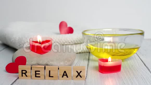 情人节水疗概念燃烧红色心形蜡烛石头按摩油单词放松和白色毛巾视频的预览图