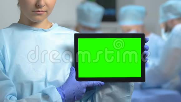 穿着制服的年轻女性显示绿色屏幕平板电脑诊所应用程序健康视频的预览图