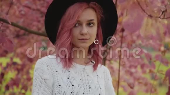 神秘女孩脸上带着微笑轻松地摆在粉红色的树上视频的预览图