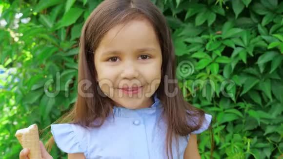 穿着蓝色连衣裙的小可爱和有趣的女孩做鬼脸吃冰淇淋视频的预览图
