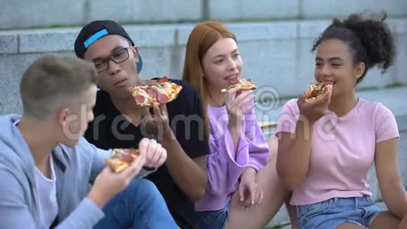 微笑着多民族的青少年在户外享受美味的披萨视频的预览图