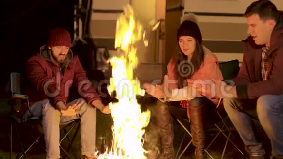 在一个寒冷的秋夜朋友们在篝火旁暖暖手的手持镜头视频的预览图