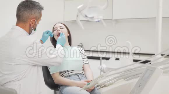 年轻的女性病人在牙科医生检查她的牙齿视频的预览图