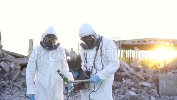 两名穿着防护服和面罩的科学家和一个个人电离辐射剂量计步行测量辐射对视频的预览图