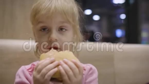 美丽快乐饥饿的女婴吃汉堡包概念儿童快餐视频的预览图