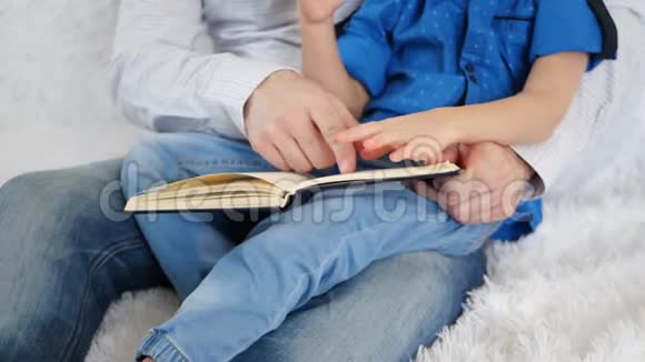爸爸和他的儿子正在看书爸爸和儿子的手紧紧地拿着一本书视频的预览图