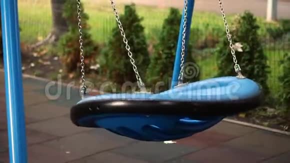 蓝色大现代圆形塑料吊链空荡在儿童游乐场在城市公园或后院绿色针叶树视频的预览图