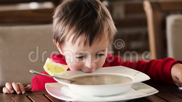 小男孩在餐桌上吃汤和面包视频的预览图