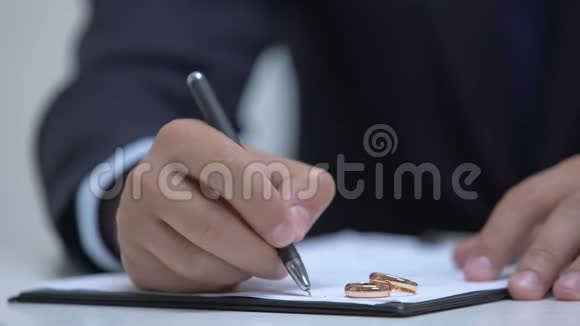 律师写婚约两个结婚戒指躺在文件上离婚视频的预览图