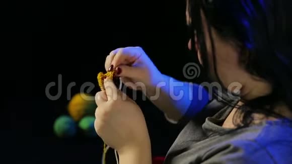 女人的手黑色的背景编织在黄色线的圆形针上视频的预览图