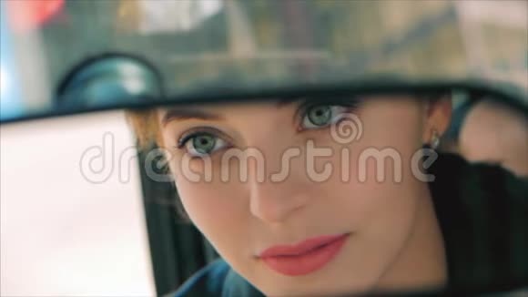 年轻美丽的女人在后视镜里看红唇女司机在后视镜里视频的预览图
