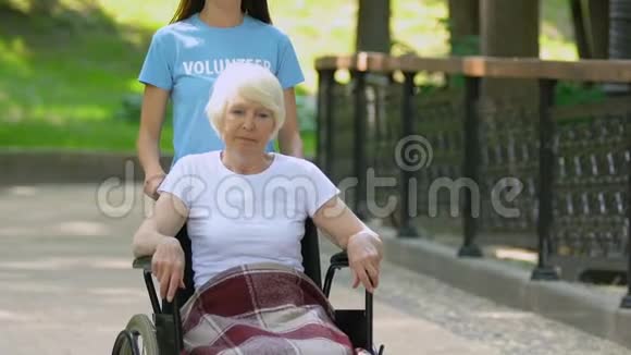 帮助轮椅上的老年女性病人在医院公园行走视频的预览图
