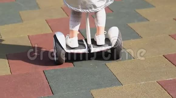 在城市公园户外的儿童游乐场里一个可爱的学龄前女孩骑着白色的小黑板视频的预览图