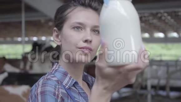 奶牛场年轻女职工画像检查奶瓶特写中牛奶质量积极的农民视频的预览图