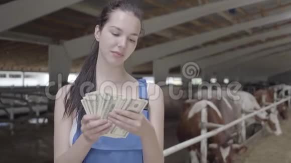奶牛场上年轻可爱的女农工画像数现金积极的农民从农场得到收入视频的预览图