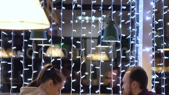 一对夫妇坐在咖啡馆里聊天喝咖啡使用智能手机视频的预览图
