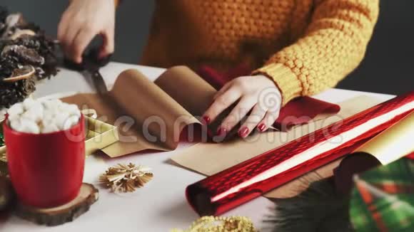 女人剪红纸用圣诞装饰把圣诞礼物包在桌子上视频的预览图