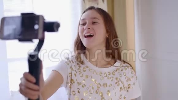 年轻的快乐女孩笑着用手机与朋友在线视频聊天在社交媒体上写博客视频的预览图