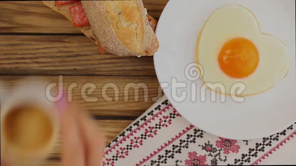 提供早餐心形的煎蛋三明治和一杯咖啡视频的预览图