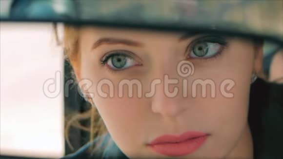 年轻漂亮的女人看着后视镜涂着红色的口红嘴唇女司机在后视镜里看视频的预览图