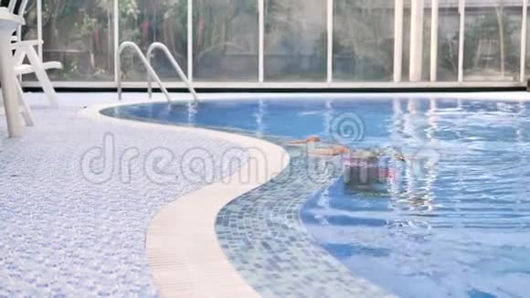 穿着粉红色泳衣的金发女郎带着清澈的蓝色海水从游泳池里出来视频的预览图