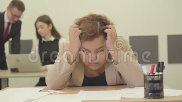 紧张的女人坐在前台的桌子旁用手抱着她的头她在工作上有麻烦青年视频的预览图
