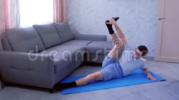 疯狂的书呆子正试图伸展他的腿躺在家里的垫子上体育幽默概念视频的预览图