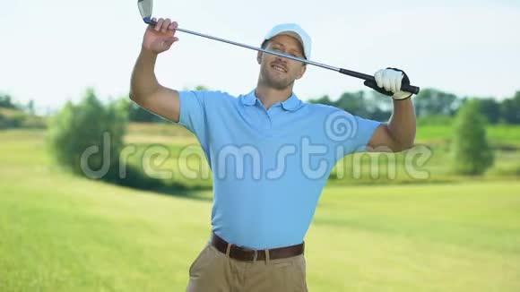 自信的高尔夫球手背后有球杆在球场上对着镜头微笑运动视频的预览图