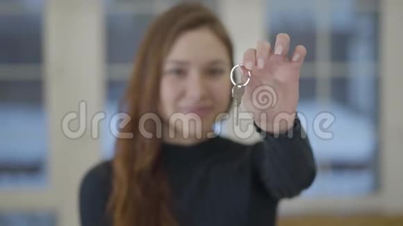 一个快乐可爱微笑的女人的肖像向相机展示一所新房子或公寓的钥匙重点视频的预览图