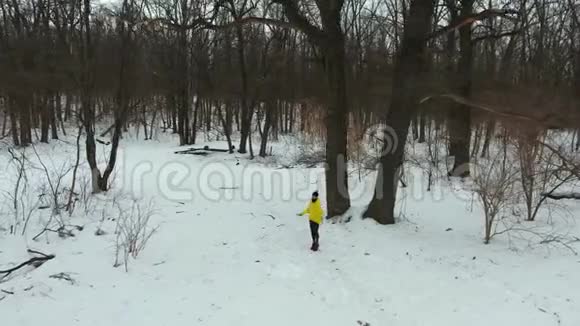 冬季森林中穿黄色外套跳绳的运动员的弧形镜头视频的预览图